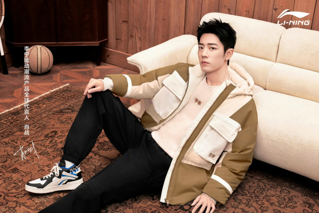 Обои картинки фото мужчины, xiao zhan, актер, куртка, кроссовки, диван, мяч, ковер