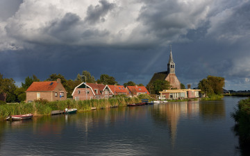 Картинка города -+пейзажи облака река нидерланды церковь oudendijk дома солнце небо камыши деревья лодки тучи