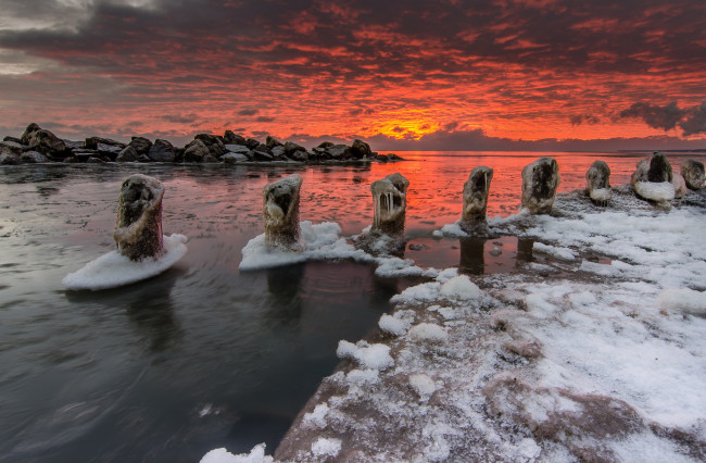 Обои картинки фото природа, восходы, закаты, камни, океан, лед, сваи, зарево, тучи