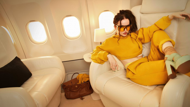 Обои картинки фото девушки, dove cameron, шатенка, очки, костюм, кресла, самолет