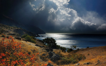 Картинка природа побережье горы лучи солнца тучи небо трава кусты камни крым Черное море пасмурно