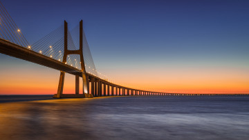 Картинка города -+мосты река тахо тежу лиссабон португалия закат оранжевый вечер небо синее освещение фонари васко да гама мост