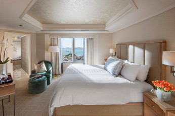 Картинка интерьер спальня дизайн стиль бежевый светлый белый комната кровать подушки столики цветы тюльпаны кресло лампы окно