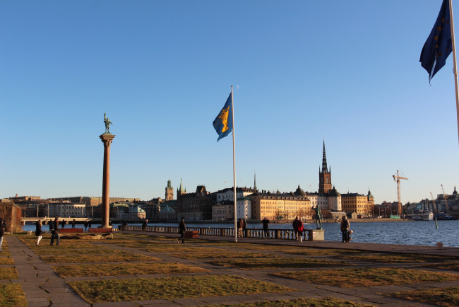 Обои картинки фото города, стокгольм, швеция, статуи, флаги, ратуша, река