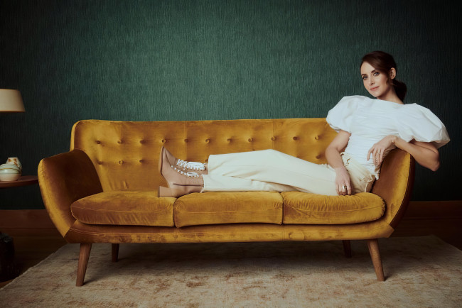 Обои картинки фото девушки, alison brie, шатенка, блузка, брюки, ботинки, диван