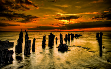 Картинка природа побережье тучи сумрак багровый закат океан сваи