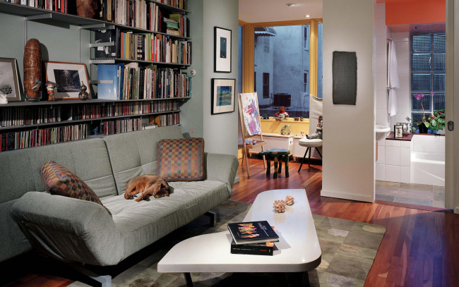 Обои картинки фото интерьер, гостиная, книги, мольберт, дизайн, диван, столик, ваза, подушки