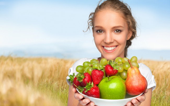 Обои картинки фото еда, фрукты,  ягоды, улыбающаяся, девушка, шатенка, с, тарелкой, яблоками, виноградом, клубникой, и, грушей, в, руках