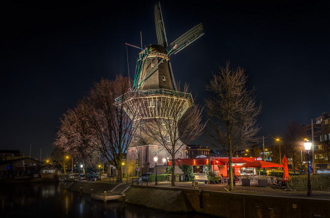 Обои картинки фото windmill in the middle of the city of amsterdam, города, амстердам , нидерланды, ночь, огни, мельница, набережная