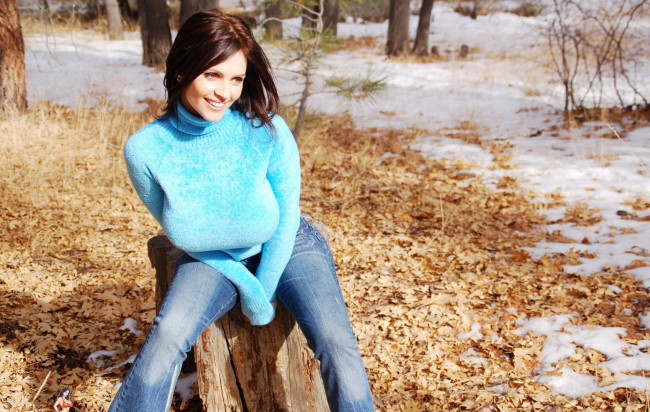 Обои картинки фото девушки, denise milani, листья, лес, пень, джинсы, свитер, улыбка, шатенка, снег