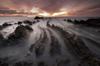 Картинка природа побережье испания баррика зима февраль вечер закат небо облака пляж скалы камни море выдержка