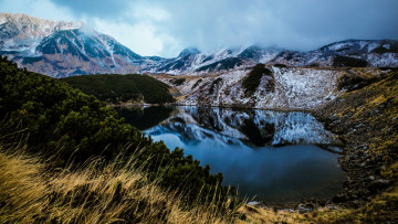 Картинка природа реки озера камни горное озеро трава пейзаж водоем хвоя снежные вершины сосны туман облака ветки холмы растительность берег зеркальное горы склон отражение