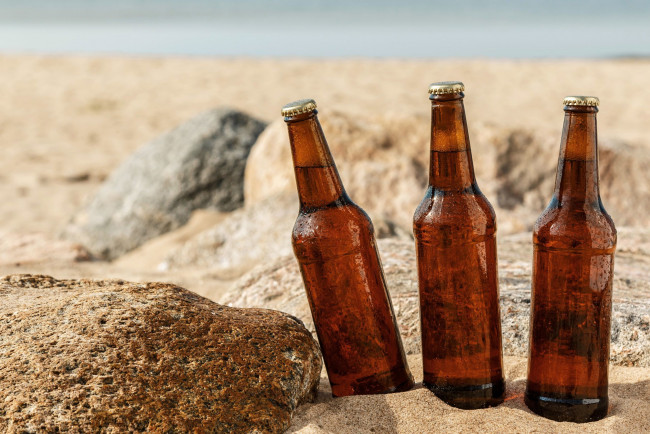 Обои картинки фото еда, напитки,  пиво, жара, бутылки, пиво, камни, песок, пляж