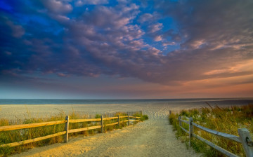 Картинка природа побережье цветное небо горизонт заборчик следы песок пляж океан
